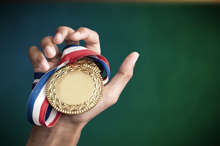 hand holding gold medal