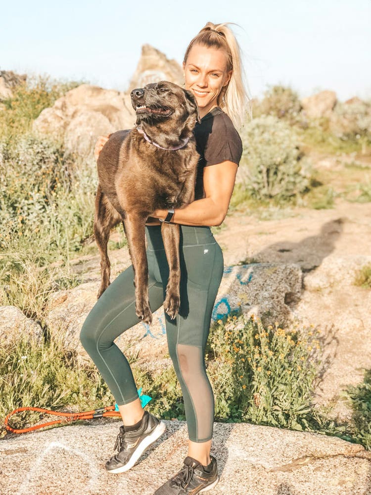 Miranda Guerra standing in the desert and smiling while holding her dog