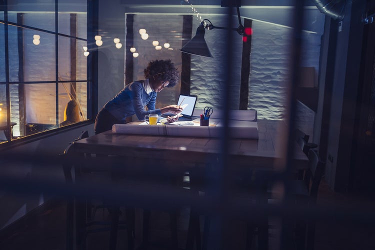 Person in a glass-walled office working late at a computer