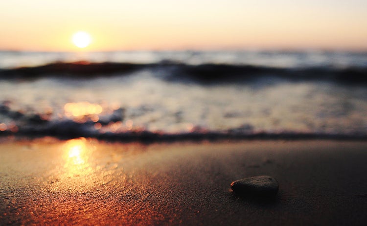 A pebble on a sandy beach at sunset