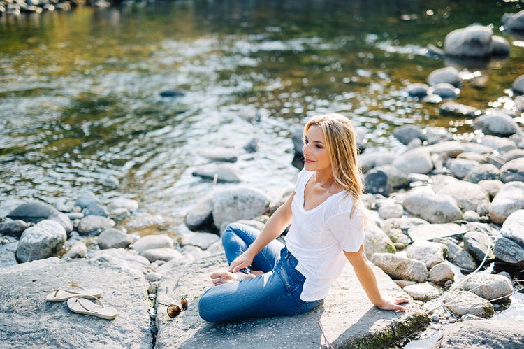 Nealy Fischer relaxes on a sunny rock next to a river