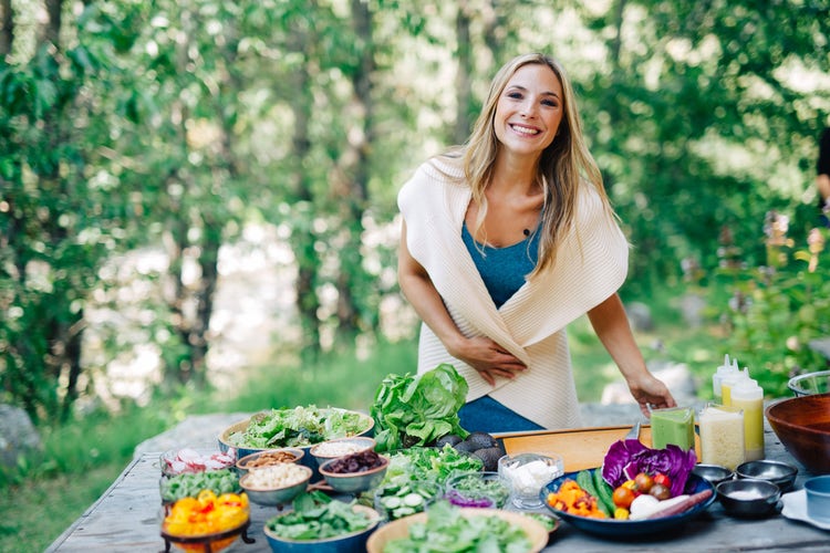Nealy Fisher stands outside smiling over a table filled with plates of vegetables