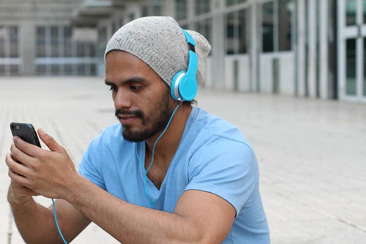 close up of man on his phone listening to music through headphones