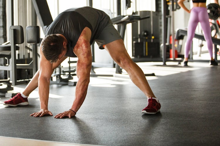 Man stretching hamstrings in forward fold at gym